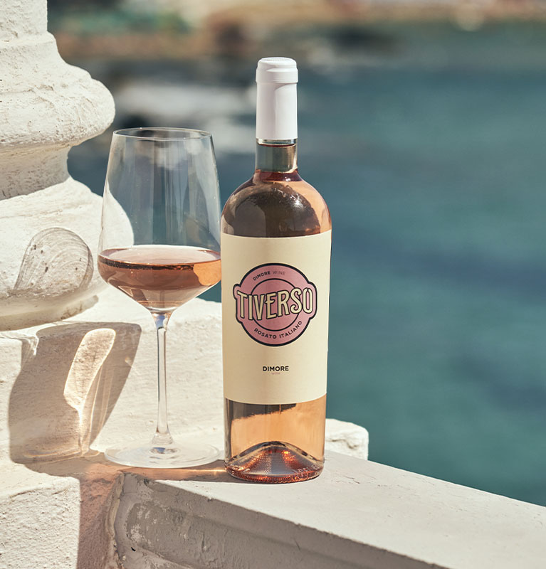 Banner homepage - Vino Tiverso con calice al lato, su un muro su uno sfondo panoramico di mare.